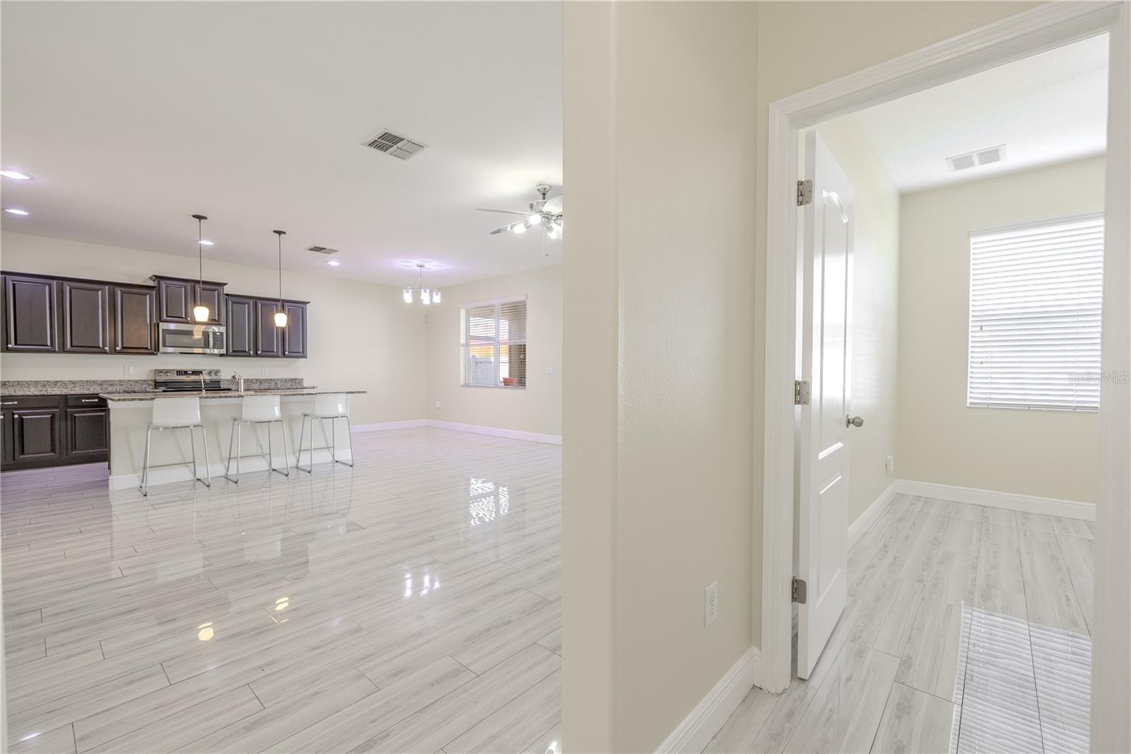 View from hallway shows kitchen/family room and downstairs bedroom.