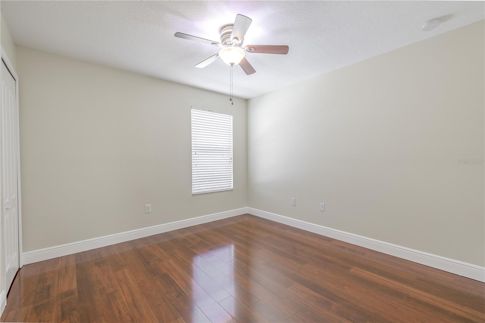 2nd bedroom features a wood floor, a walk-in closet and a ceiling fan with light kit.
