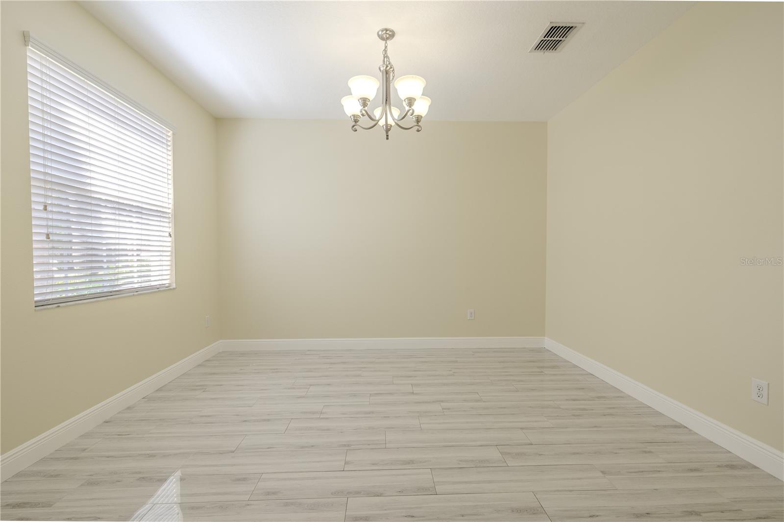 The Dining room is to the left of the foyer, features neutral tone walls, and a 5-Light Shaded Classic Brushed Nickel Finish Chandelier. This room could also serves as a formal living room or a home office.