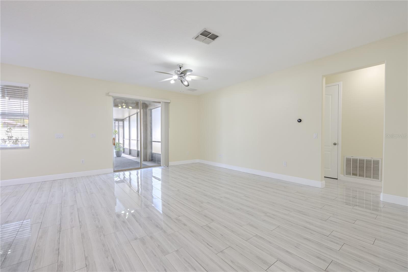 The family room features porcelain plank tile floor, a ceiling fan and neutral tones.