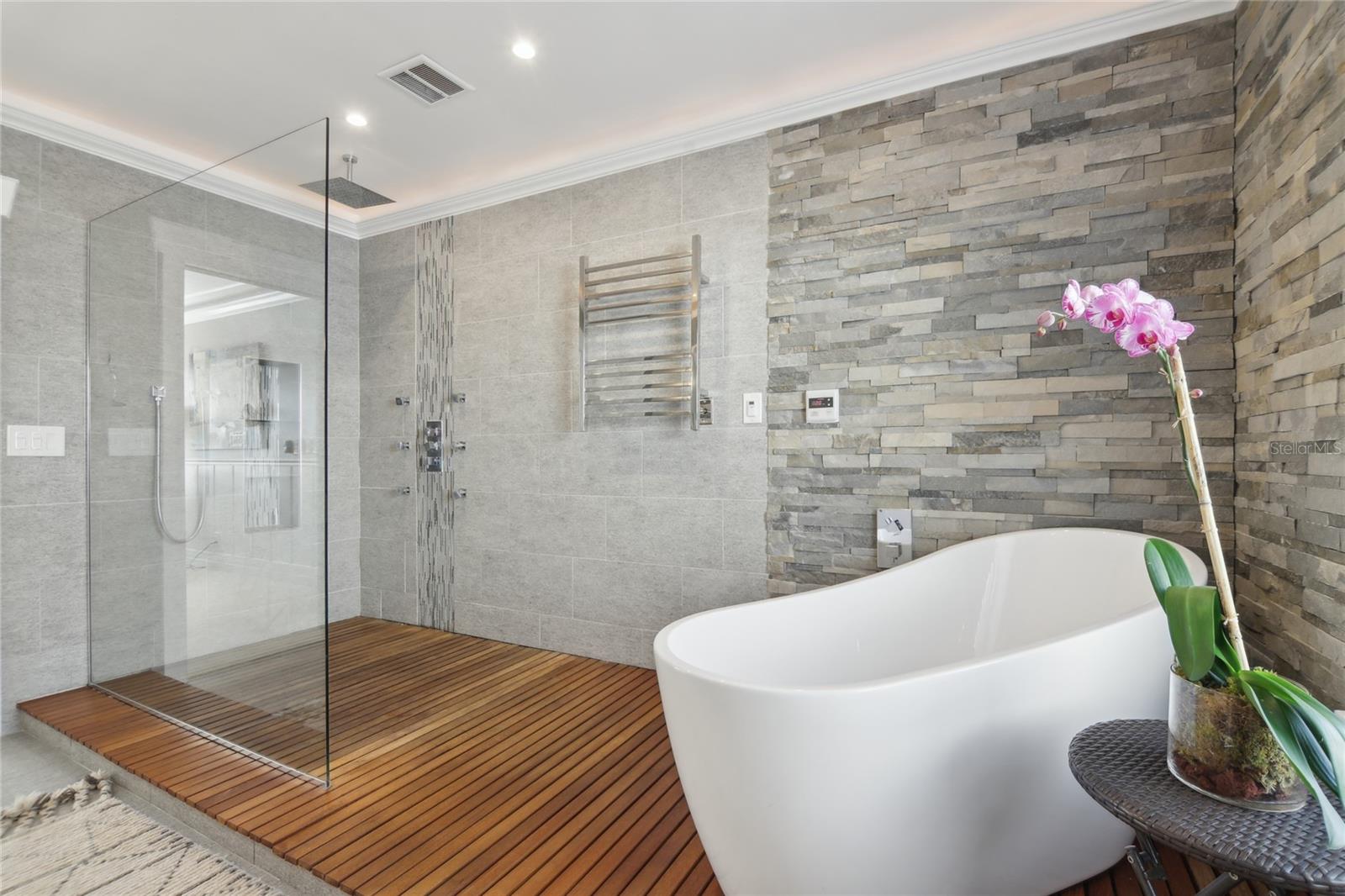 Freestanding tub with towel warmer, plus a walk-in shower featuring a rain head and body jets.