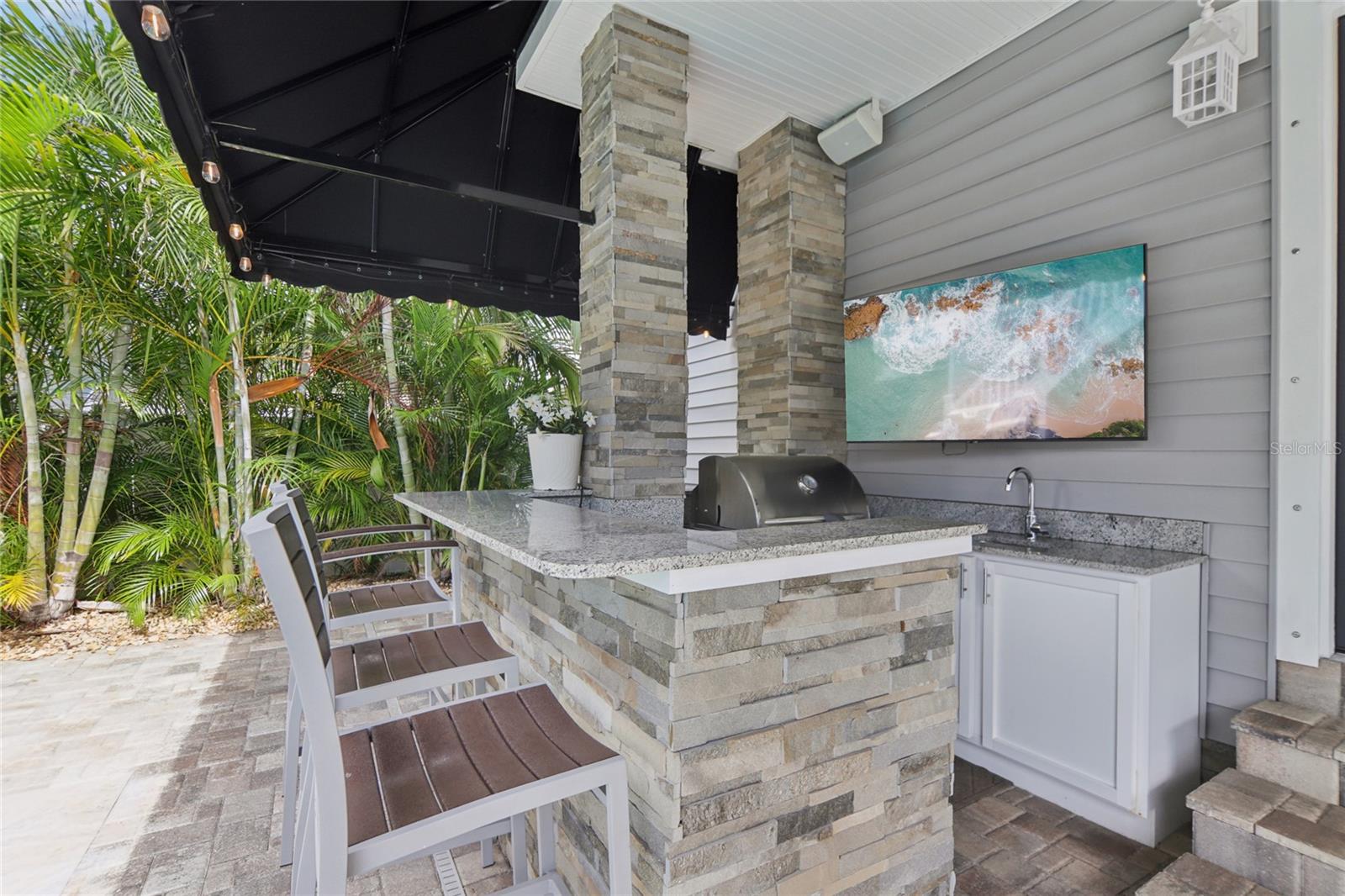 Outdoor kitchen includes a built-in Blaze grill, TV, refrigerator, and sink.