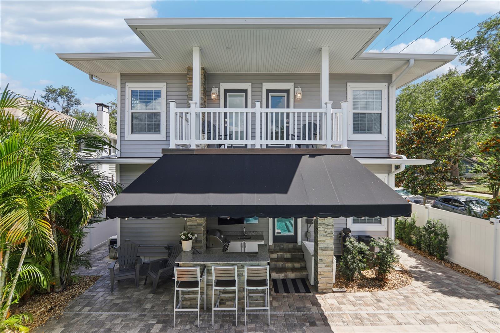 Covered and shaded outdoor kitchen. Above, the second level features the back balcony of the main home.