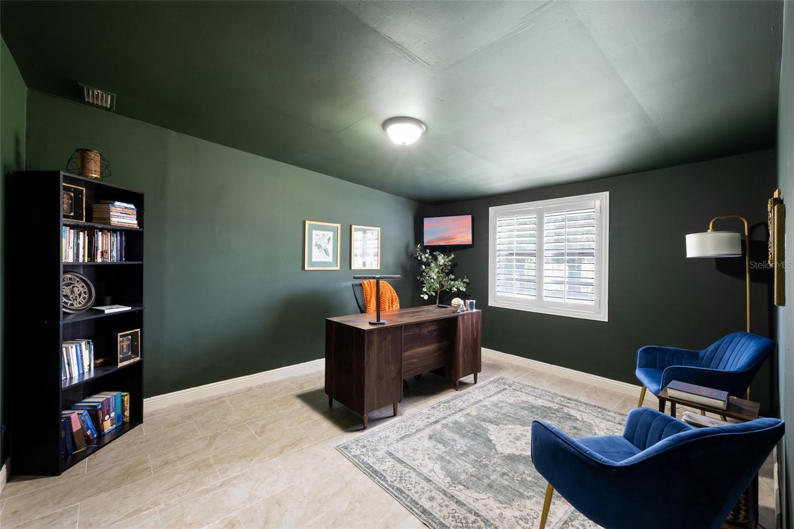 Bedroom 5 with walk-in closet and built-in shelving, plantation shutters and view of backyard