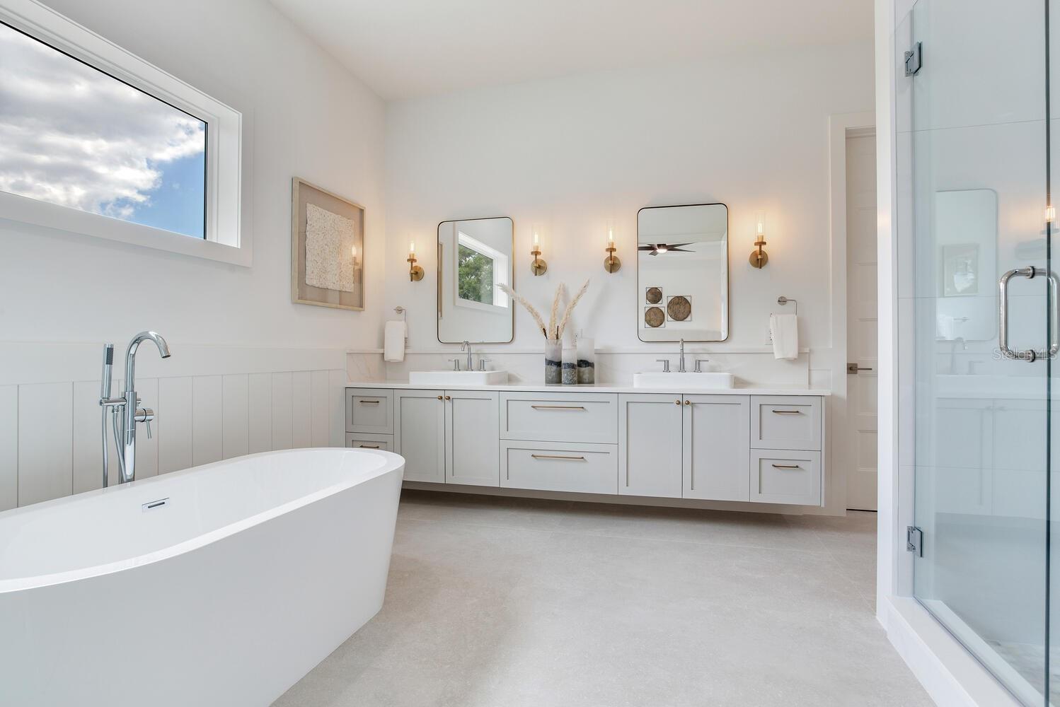 primary bathroom is highlighted by floating cabinets, soaker tub, and glass enclosed shower and raised window for natural light and privacy
