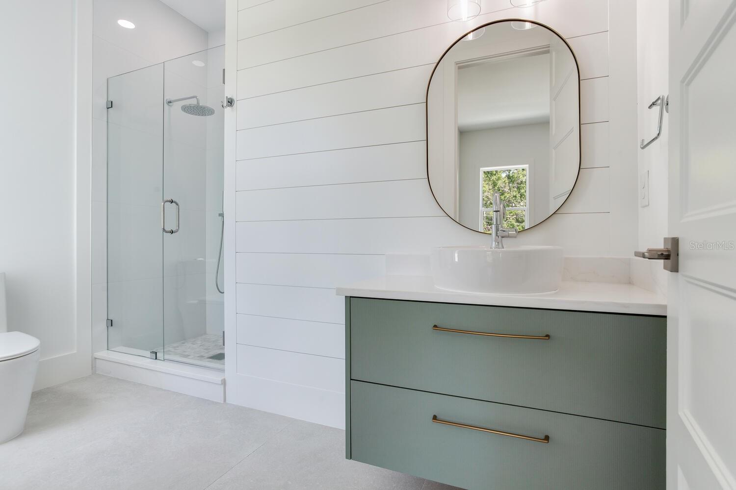Bath attached to bedroom 3 keeps the color theme and floating cabinets as well as a beautiful glass shower