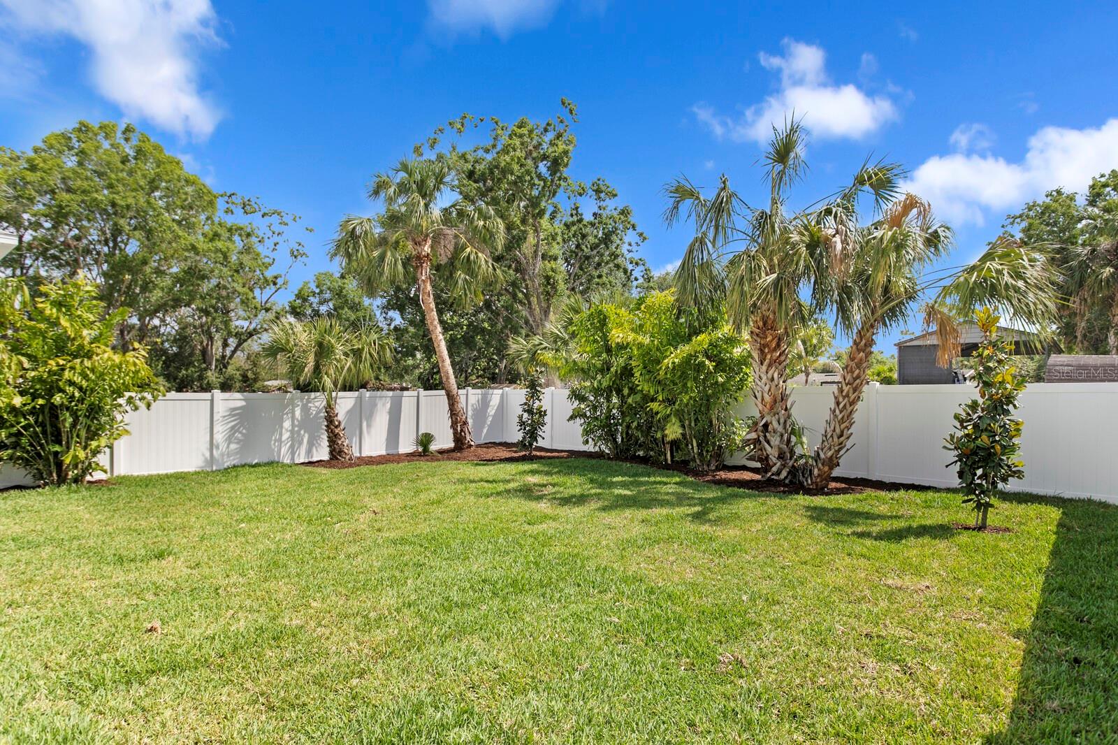 Clean and fenced backyard is landscaped and has a drain system surrounding it to direct water away