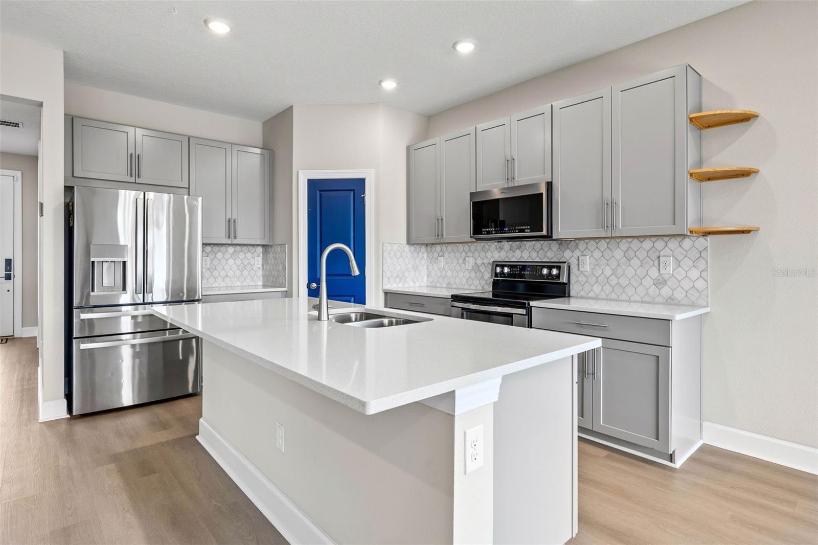 Kitchen has white quartz  countertops, stainless steel appliances, closet pantry and island seating for 4.