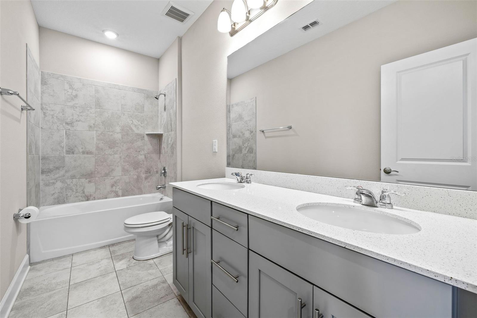 Bathroom 2, 2nd floor with dual sinks, tub/shower, and quartz countertops.