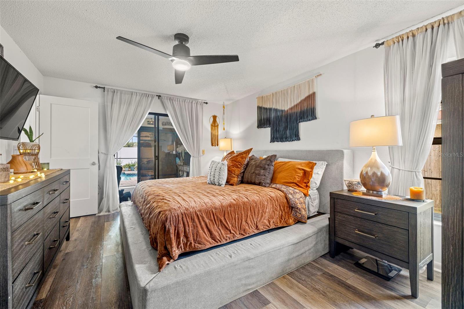 View of the primary bedroom toward the sliding glass doors that lead to the lanai & pool.