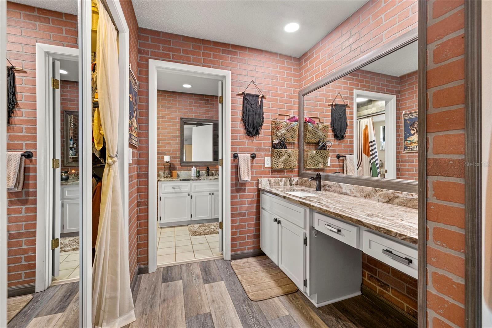 Primary en-suite bathroom features updated dual vanities, mirrors, fixtures, recessed lighting and tons of storage!