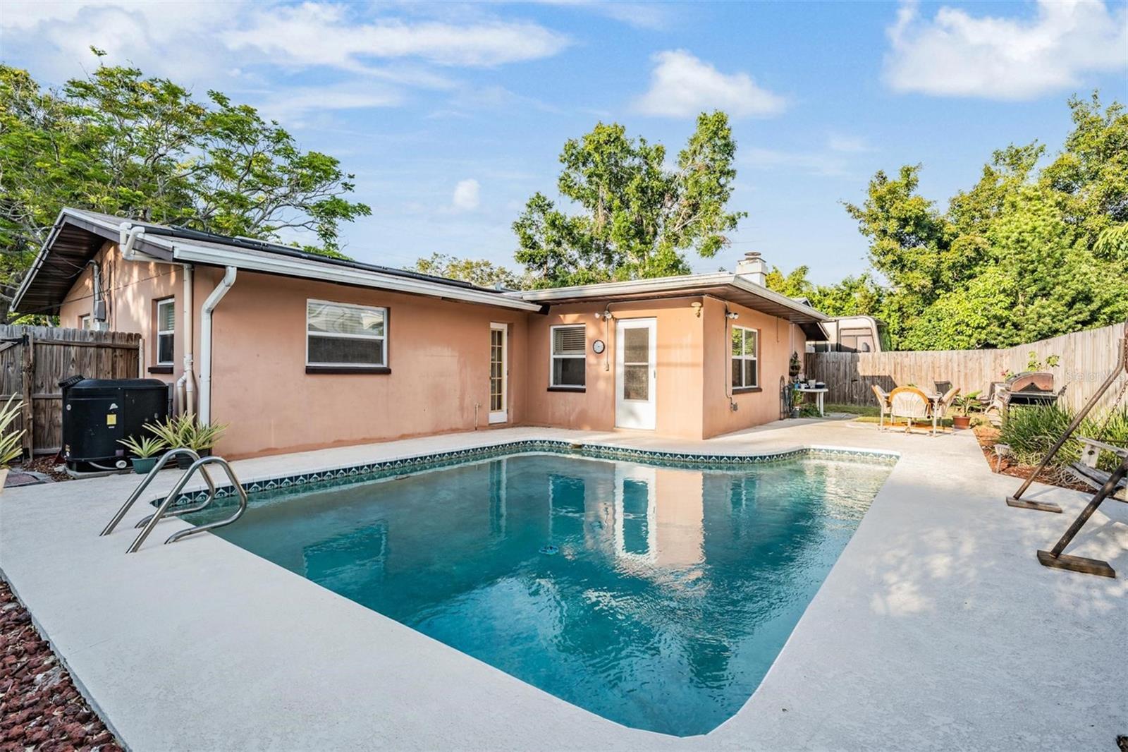 The large backyard—with a pool, seating area, grassy space, and side yard access—is perfect for enjoying the best of Florida living.