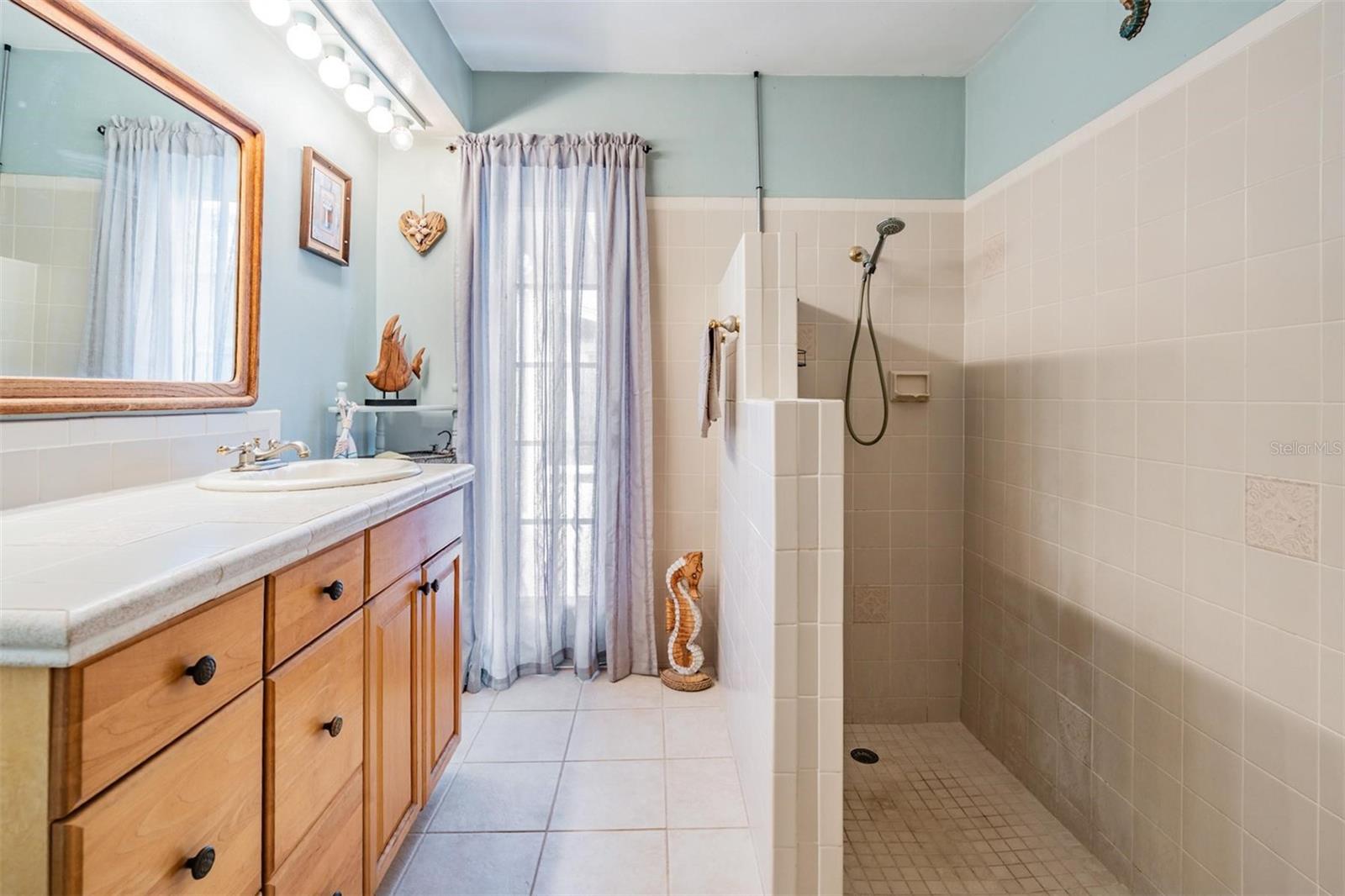 The spacious guest bathroom, featuring plenty of cabinet space, offers direct access to the pool, ensuring convenient outdoor access without bringing wet footprints into the house.