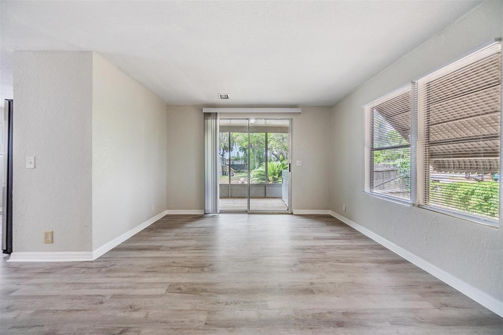 Living Room with sliders to screened lanai. NEW LUX VINYL PLANK FLOORS. NO POPCORN CEILING.  DRYWALL ON WALLS.