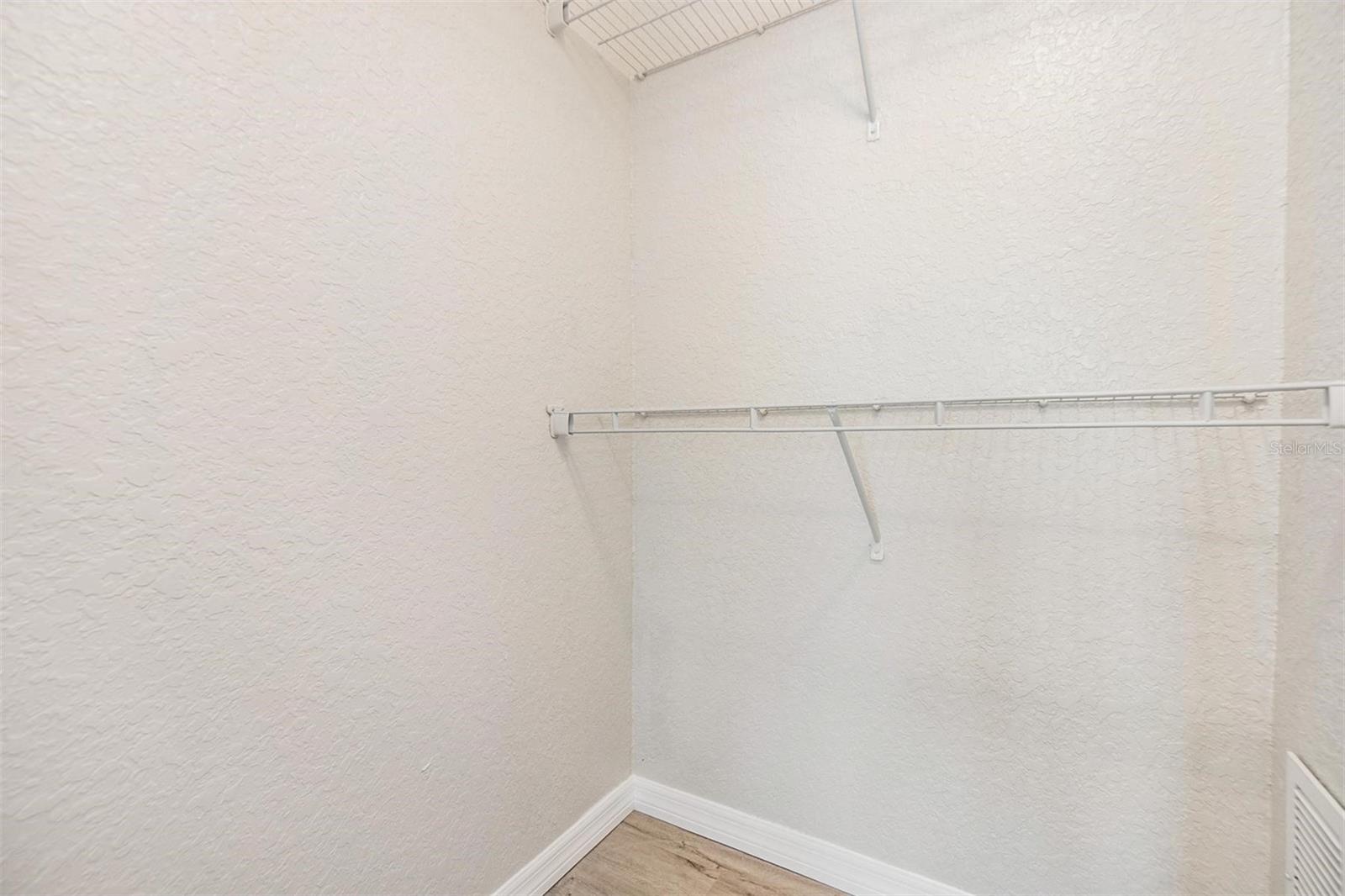 Primary Bedroom Closet.  NEW LUX VINYL PLANK FLOORS. NO POPCORN CEILING.  DRYWALL ON WALLS.