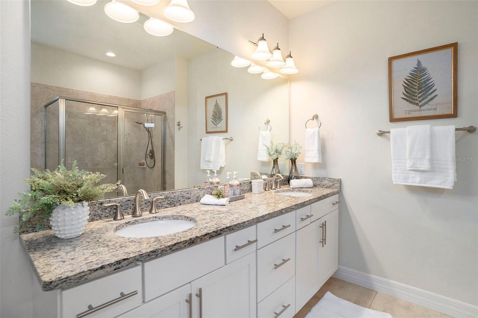 Primary bedroom bathroom with dual sink vanity, glass shower doors, deep tub, and linen closet