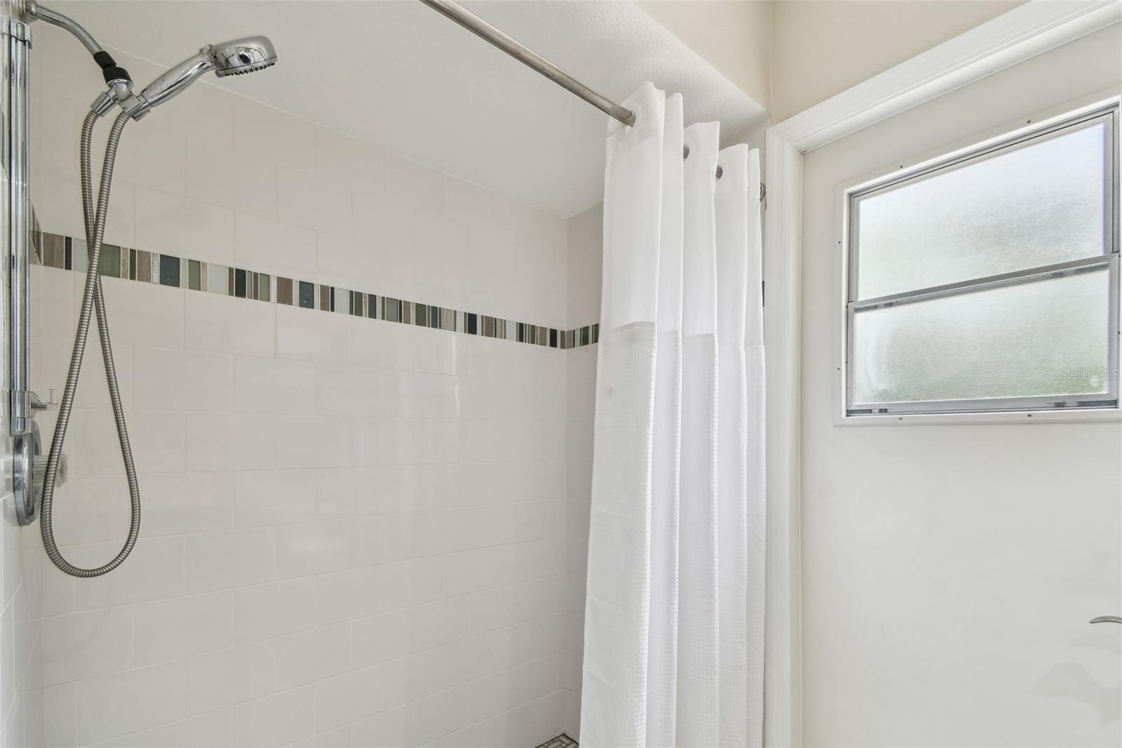 Shower in pool bath has a zero-entry (curbless) shower.
