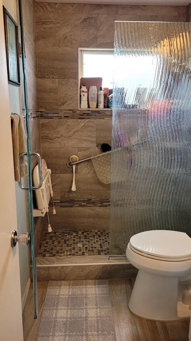 The shower has a chair that raises and lowers for convenience. Beautiful neutral tiles and handicap bars are installed for safety.