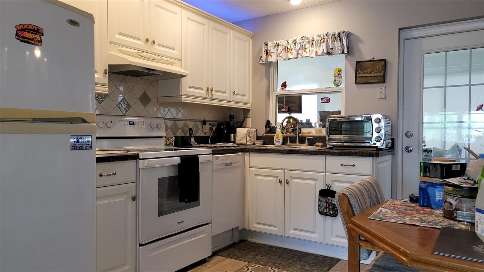 The left side of the kitchen has your appliances and sink. The door on the right leads to the screened in porch / lanai, and laundry area. The porch is currently being used for storage and blocking the beautiful views.