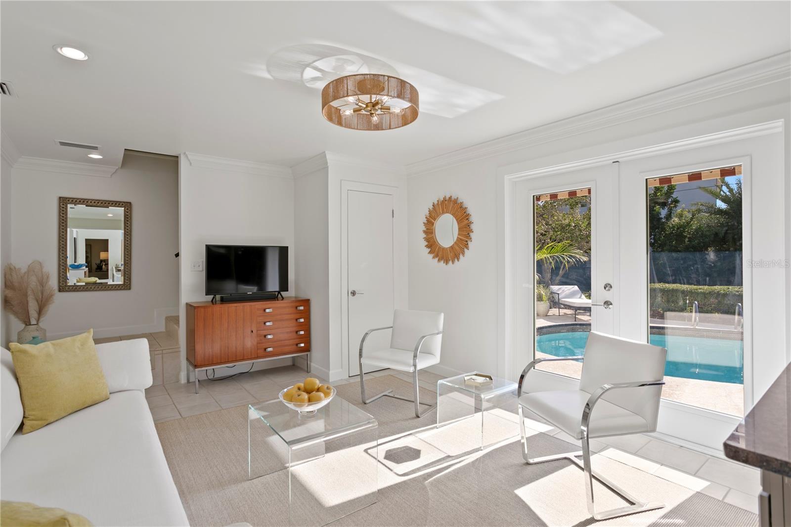 Contiguous to the kitchen, a beautiful sunroom with new high-impact glass French doors