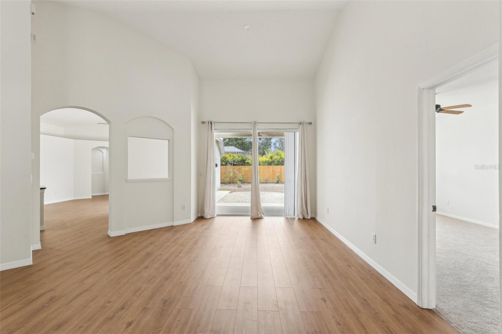 FORMAL LIVING ROOM WITH PRIMARY SUITE ON THE RIGHT AND ARCHED DOORWAY TO KITCHEN AREA