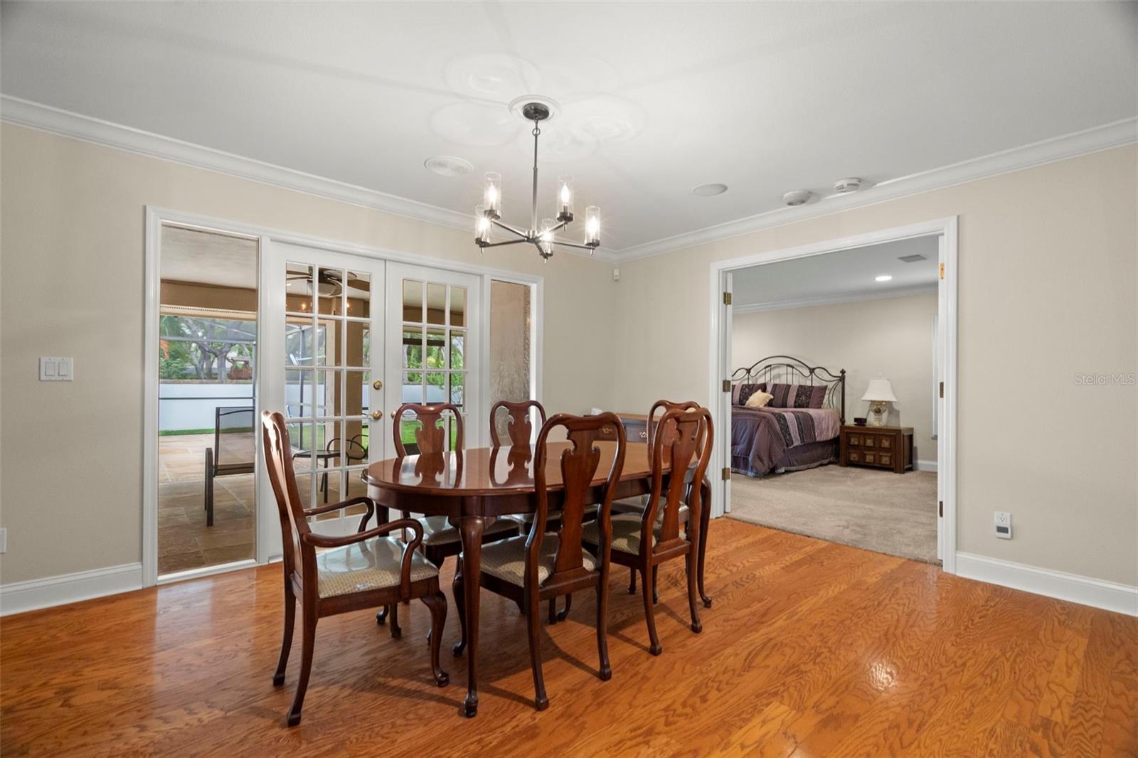 Dining room view of sliders and into Primary Bedroom with French Doors.
