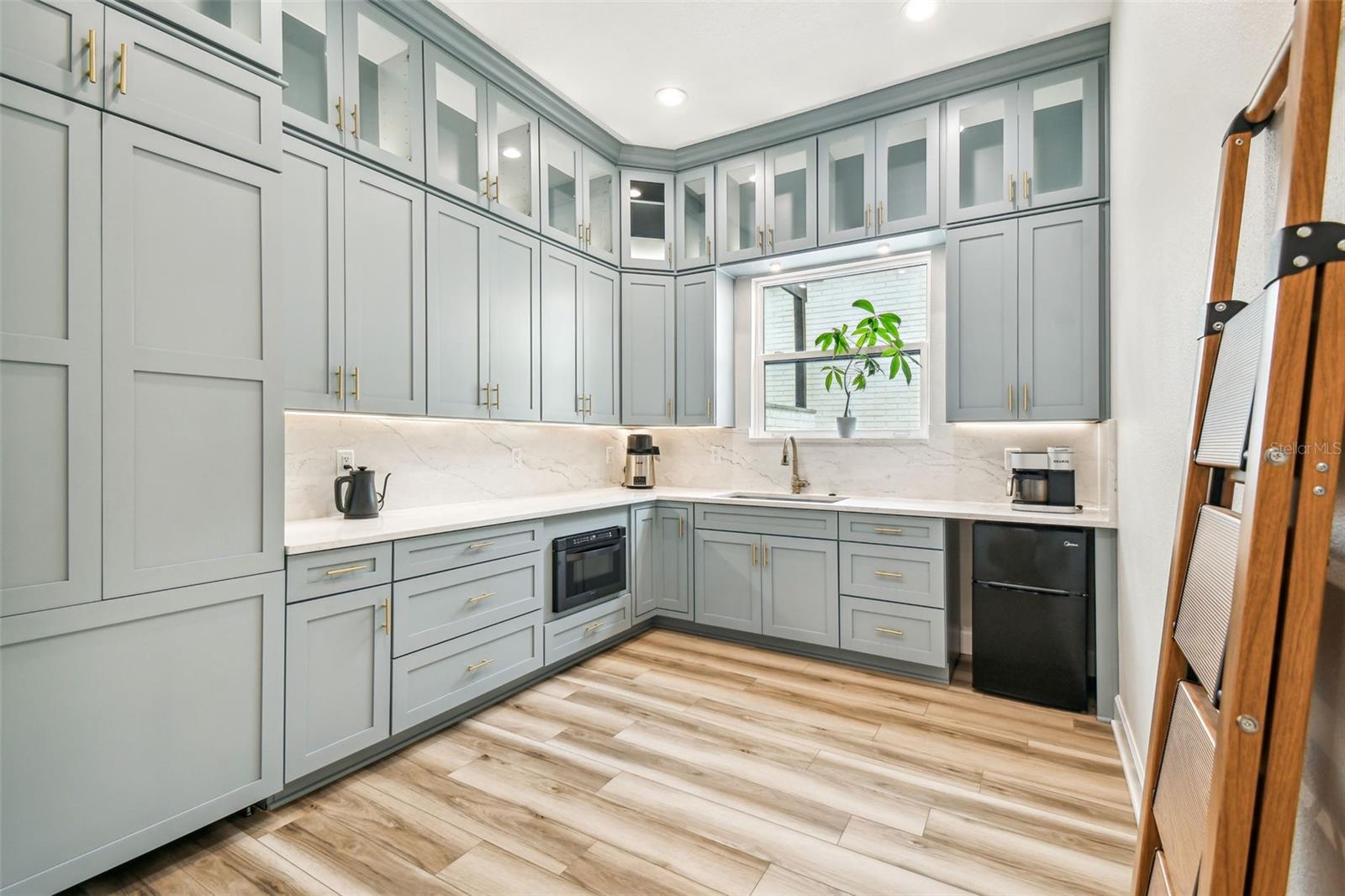 Butler's pantry with floor to ceiling cabinets and quartz countertops
