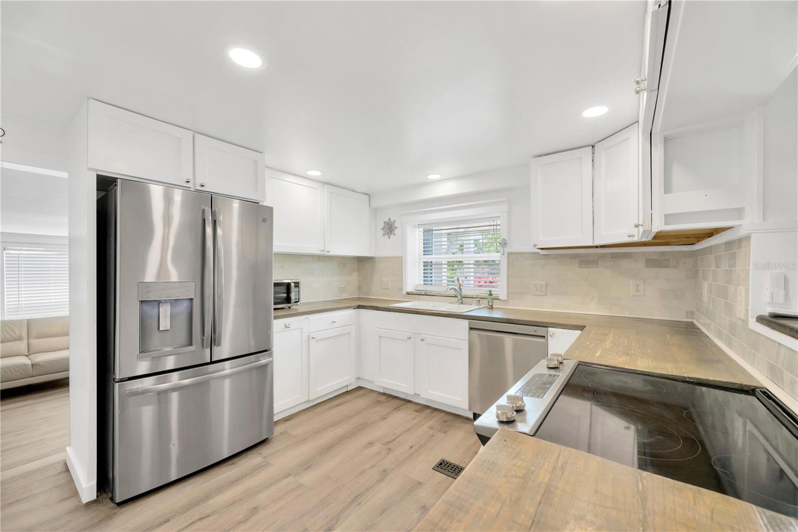 GE Profile stainless steel appliances, durable pine countertops, solid wood white cabinetry and a stunning cast iron porcelain farmhouse sink.