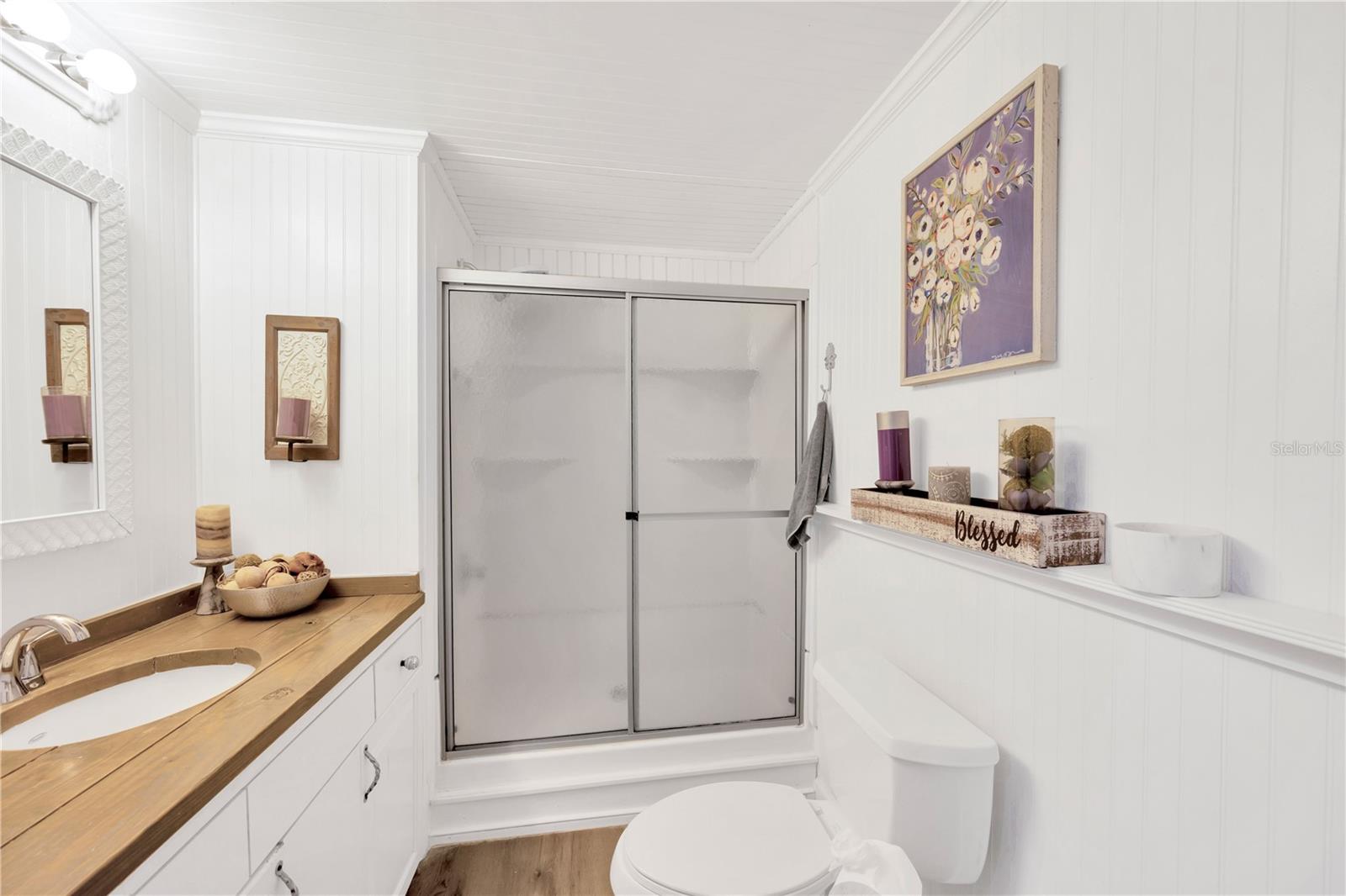 Guest bathroom clad in shiplap has pine countertops and a step-in shower.