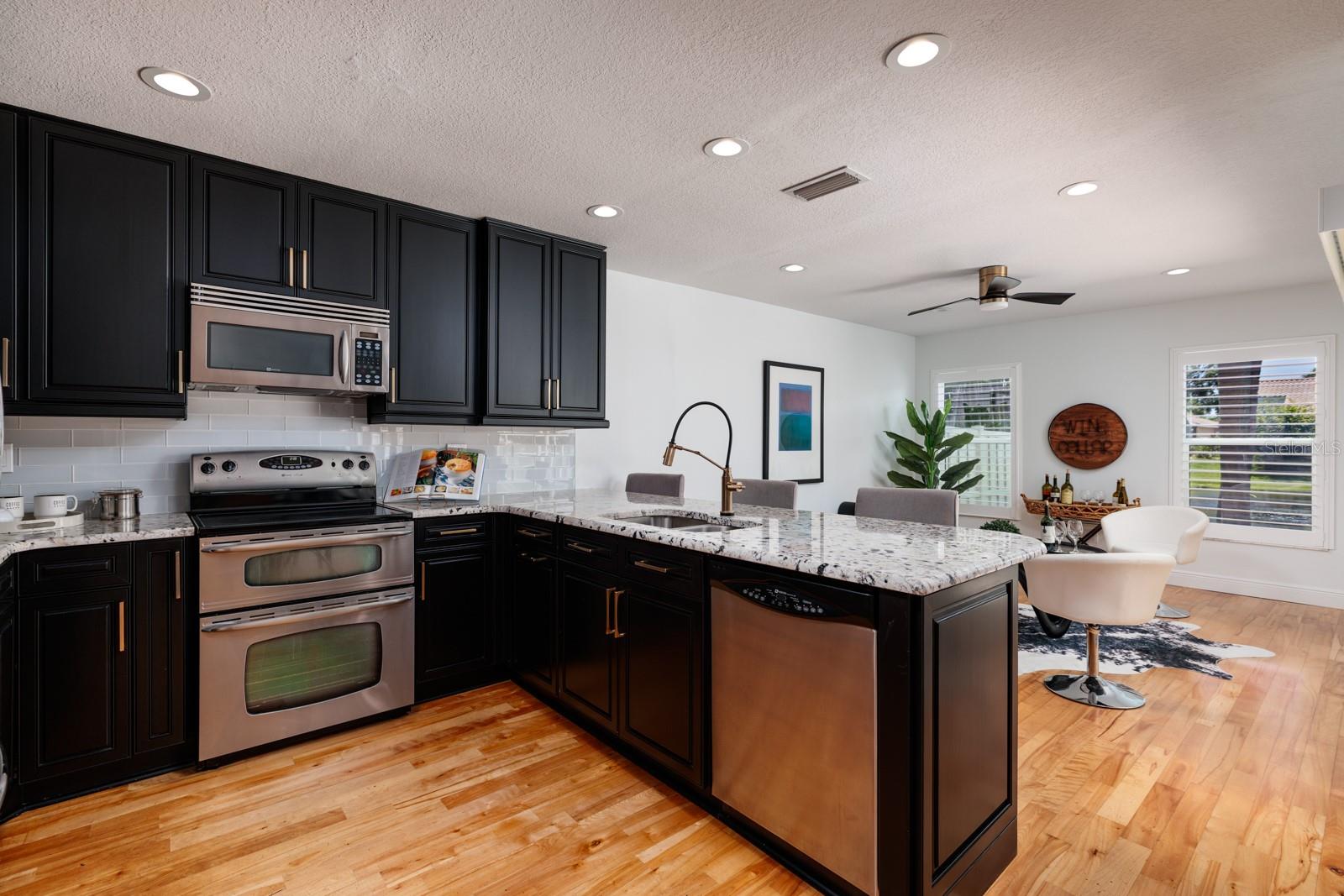 Black Satin Solid Wood Cabinets, Black and White Granite Countertops, Glass Accented Backsplash and Vented Microwave!