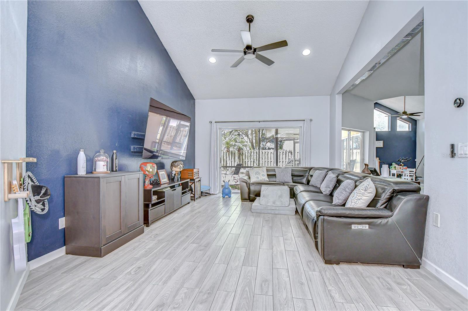 Living room has vaulted ceilings, sliders, and a gorgeous plank tile flooring!
