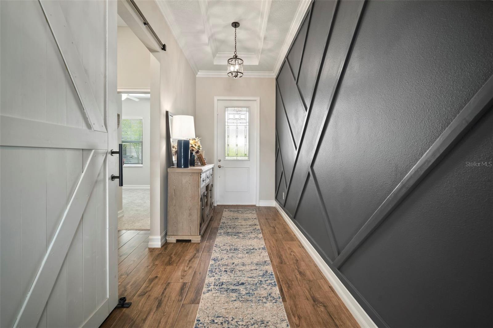 Front foyer with custom accent wall and barn door