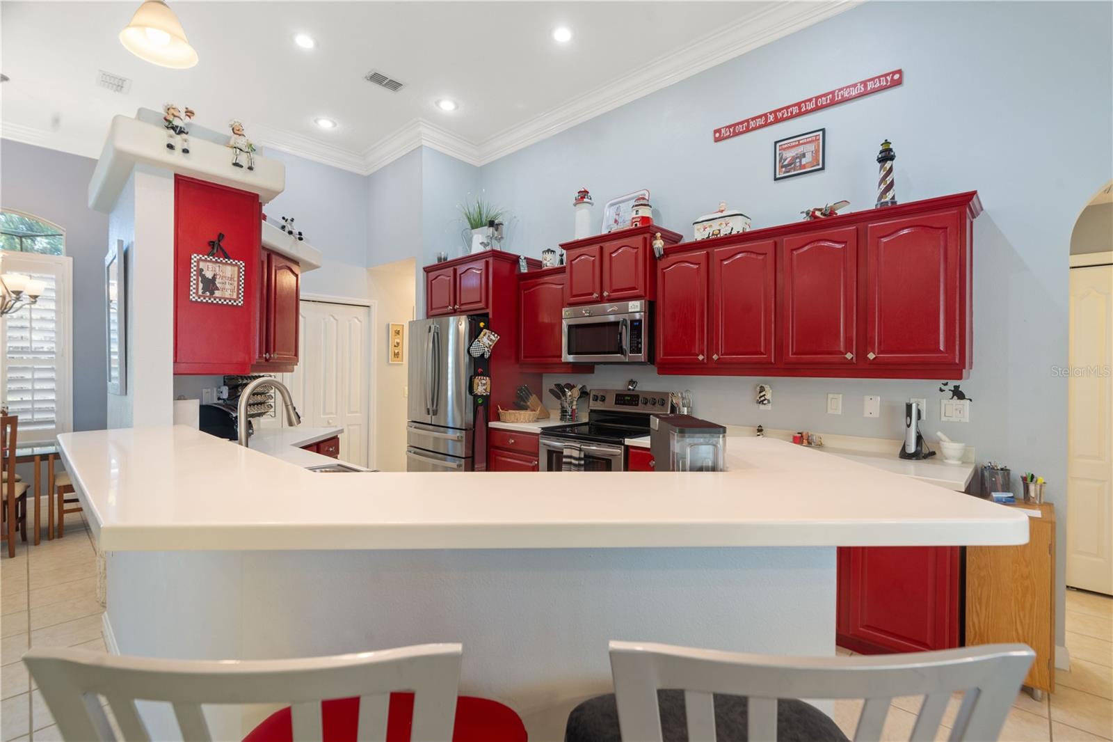 Breakfast bar at kitchen. Recessed lighting at the ceiling. White bifold doors straight ahead house the pantry.