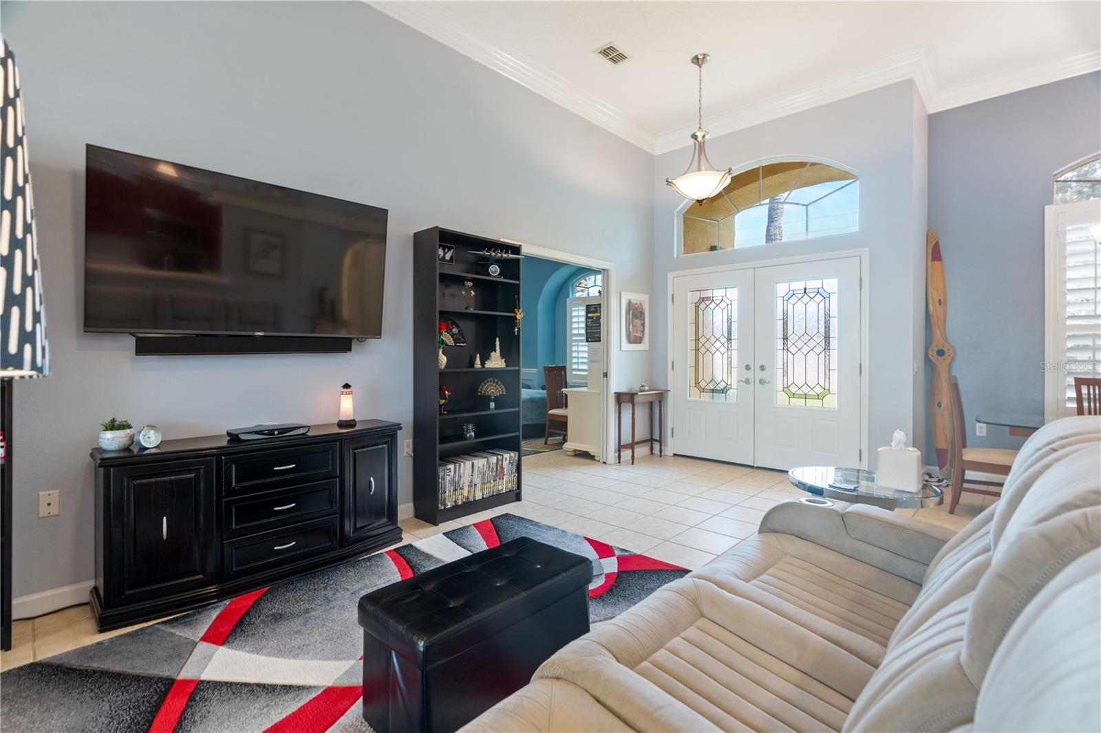 Double doors with beveled stain glass and a large transom window bring in much sunlight during the day.