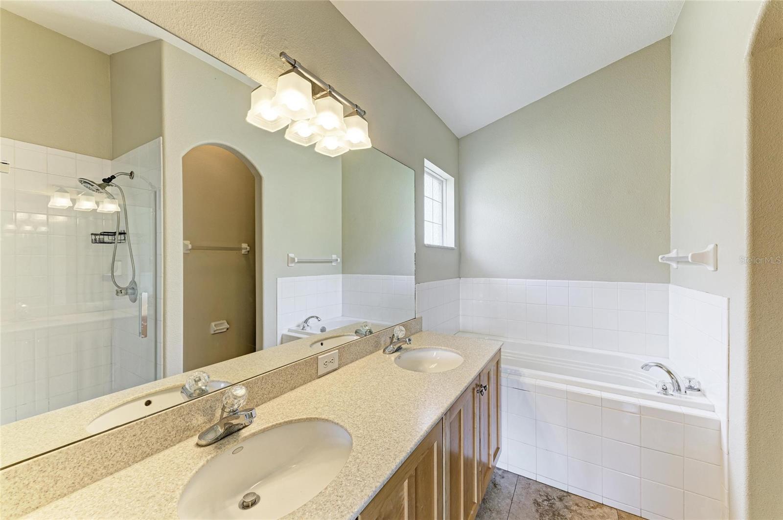 Primary en-suite bathroom with dual sinks, garden soaking tub and stall shower