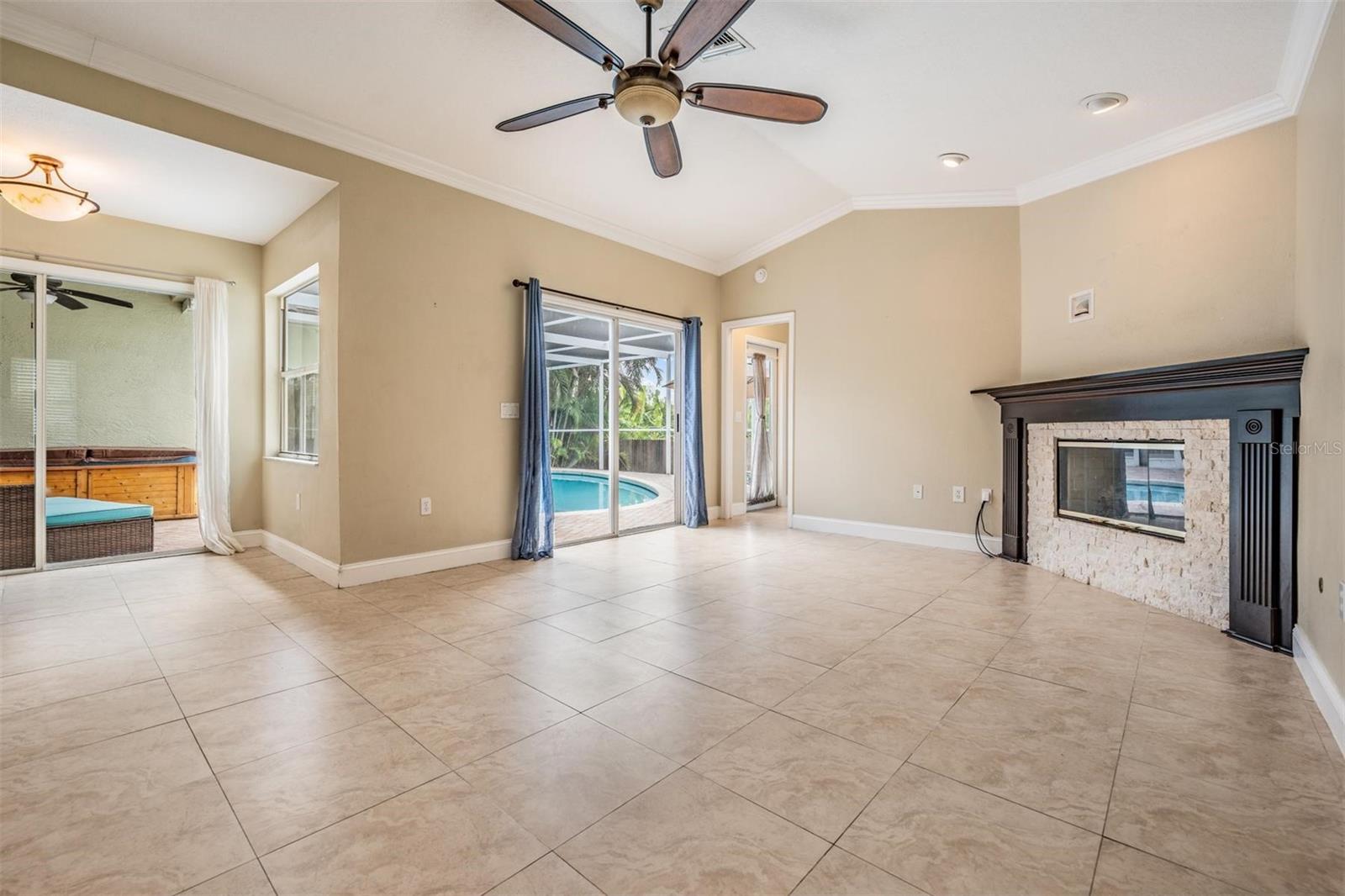 Large family room with easy-care tile and view of pool