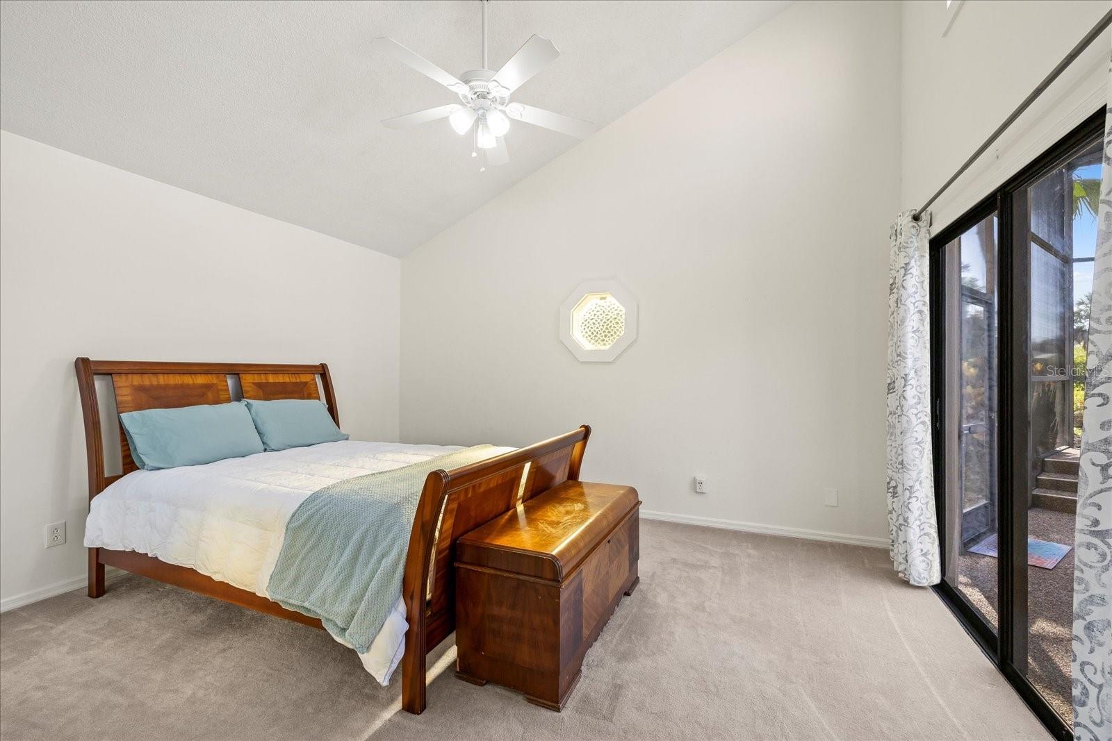 Large bedroom with soaring vaulted ceilings and sliders to the beautiful pool lanai.