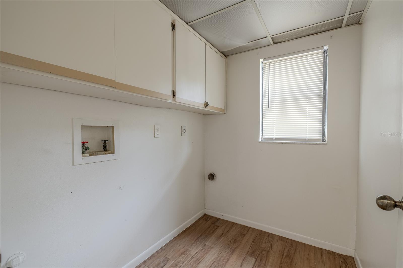 The laundry room features washer and dryer hook-ups, overhead cabinets and a laminate floor.