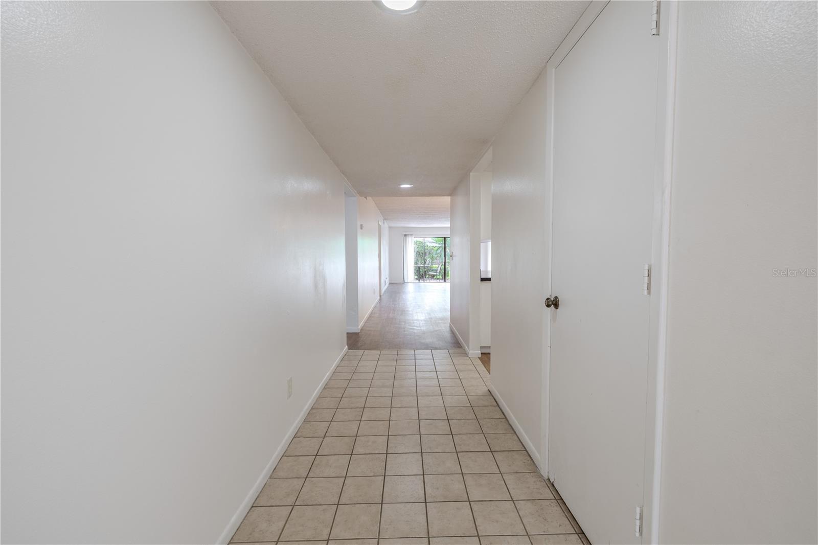 The foyer is neutral toned with a tile floor and a coat closet.