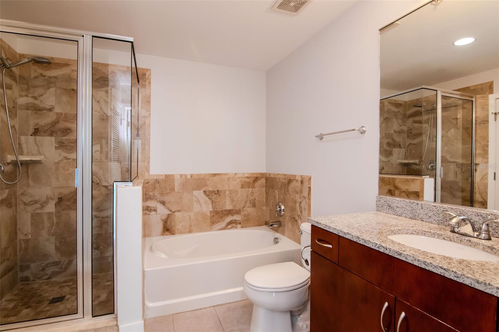 tiled shower, separate soaking tub, granite-top vanity, and designer fixtures.