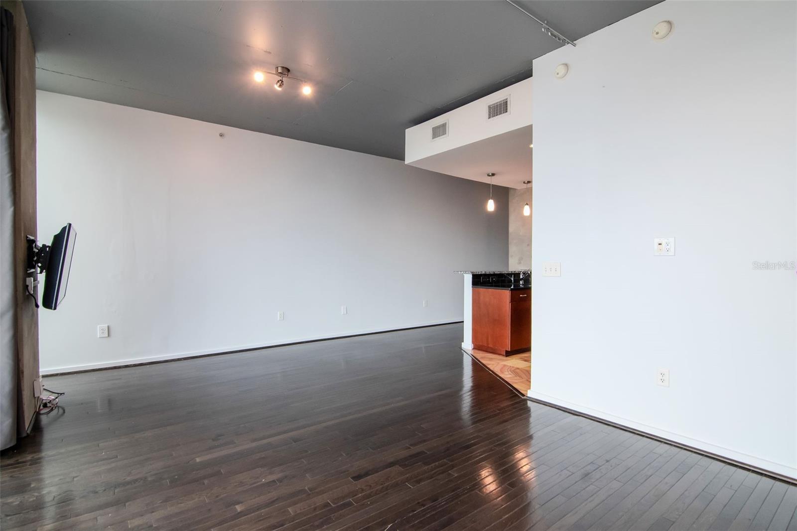 Expansive living area with floor-to-ceiling windows, dark hardwood floors, and panoramic cityscape views.