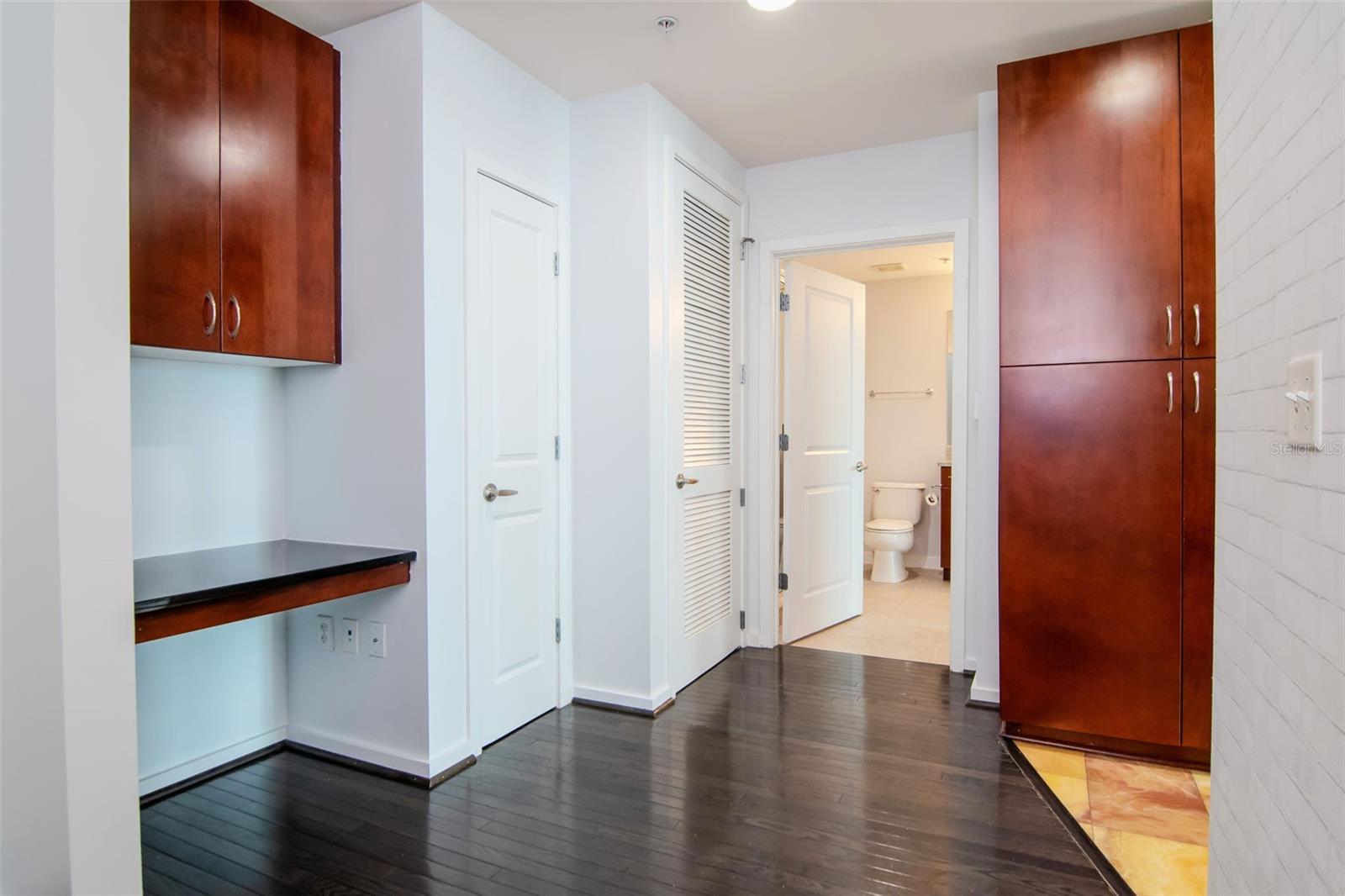 Versatile built-in desk with overhead storage and direct access to laundry and bath.