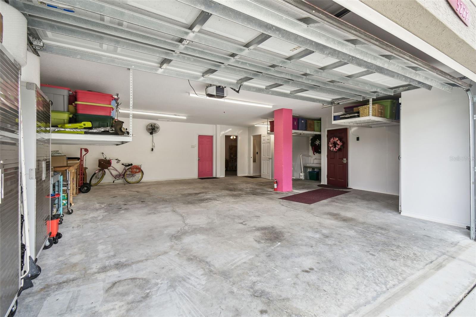 Oversized garage. First door on your right (maroon with a wreath) provides access towards living space. Second door on your right (white door) is for the pool bath. Open door leads to the storage room.  Pink door leads outside.