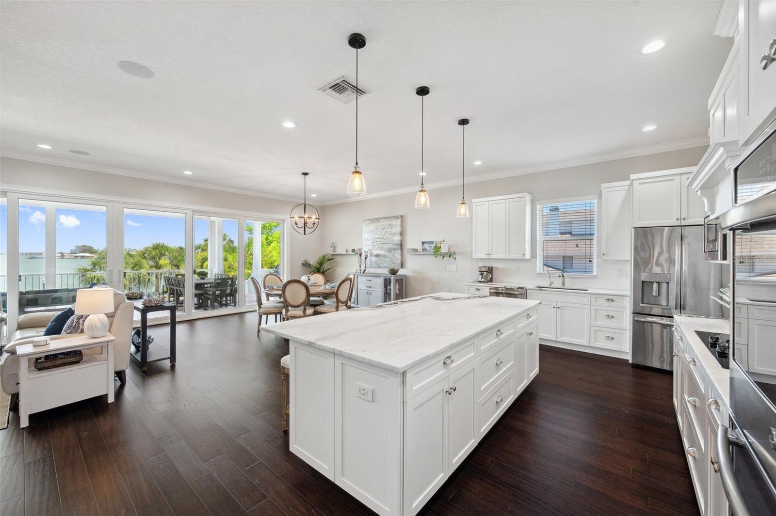 Open concept! Here is a view of the kitchen, dining, and living space with a dreamy intracoastal water view out the sliding glass doors.