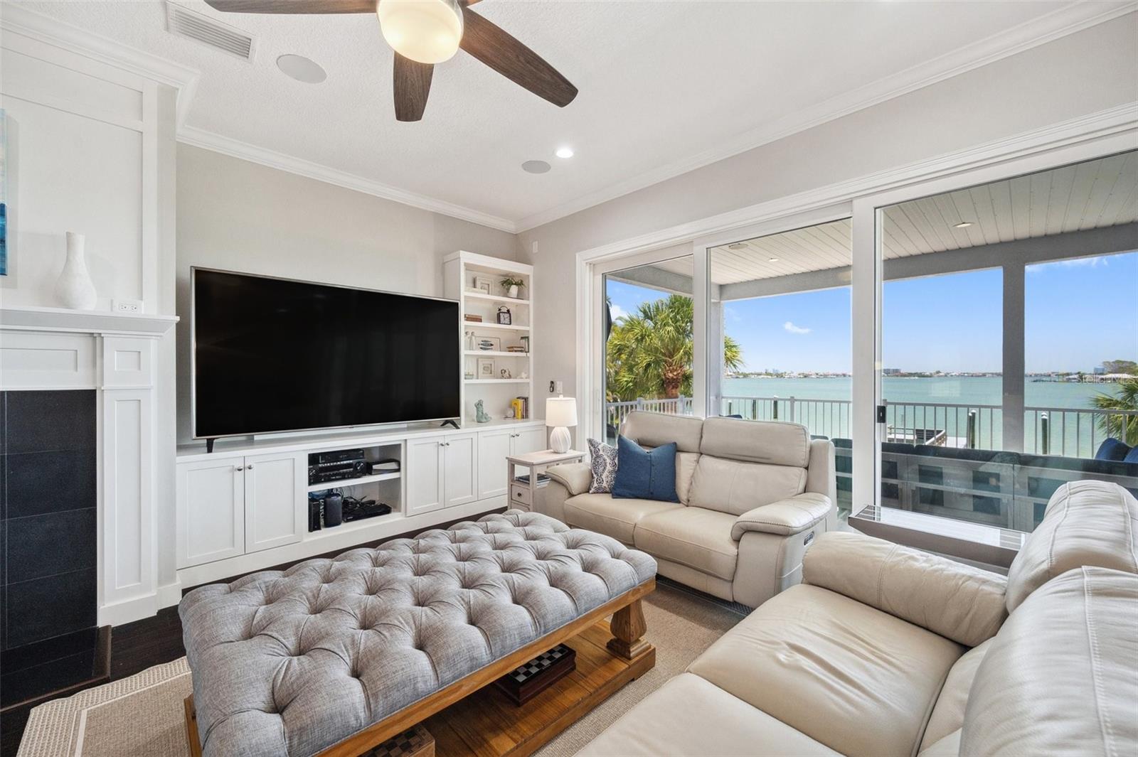 This living room not only features a dreamy water view, but also custom wood cabinetry, built-ins, and a wood burning fireplace surrounded by black granite and a custom mantel.
