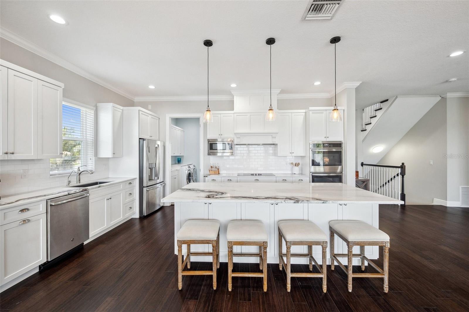 View of kitchen and center island. Pantry/laundry room in back left of photo.
