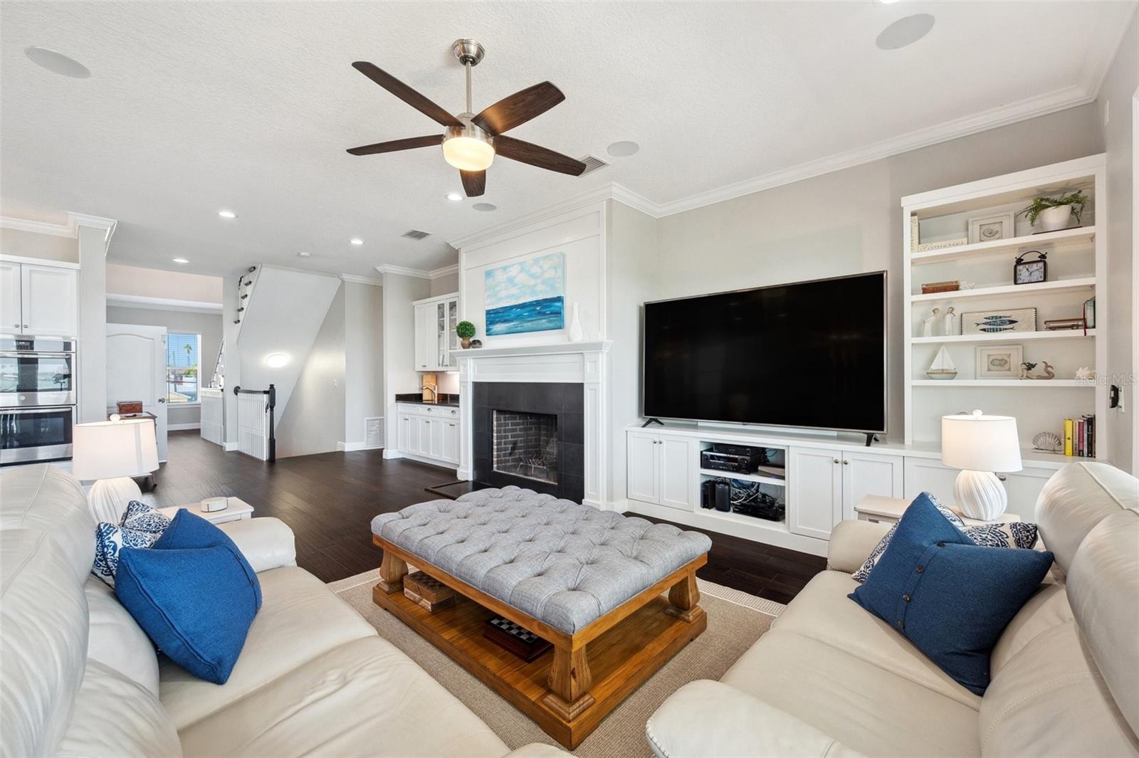 View of the primary living area, showcasing the luxury custom DuraSupreme cabinets, fireplace mantel and trim, built-ins and bookcase.