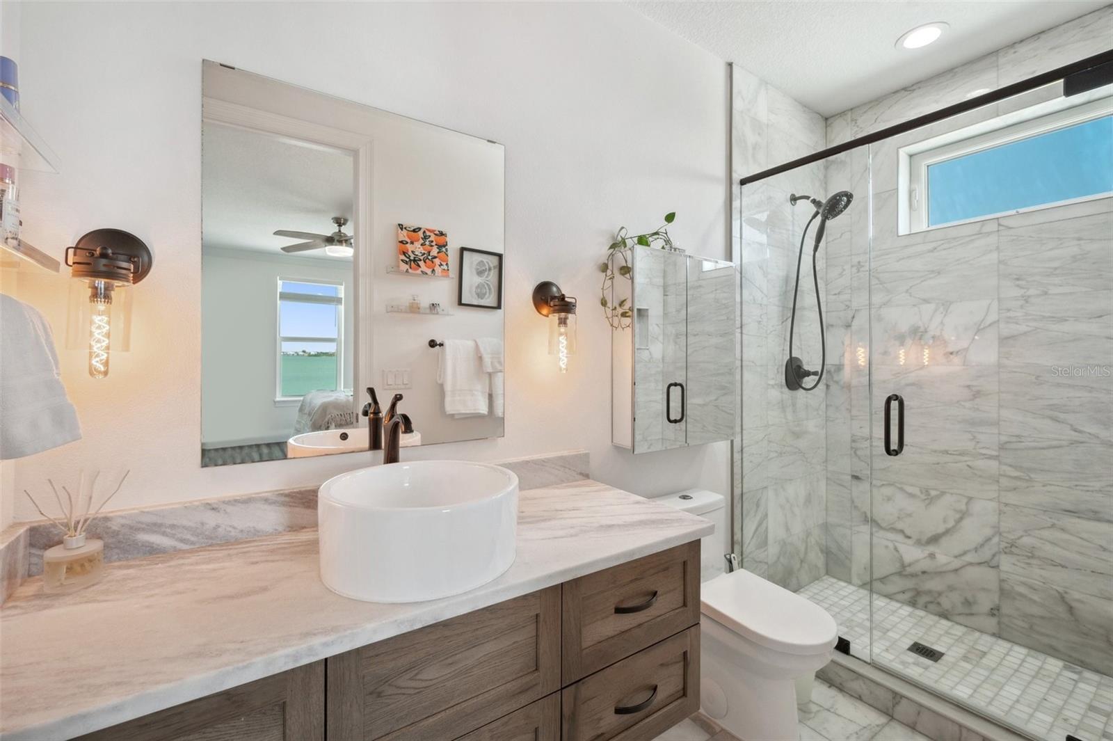 The secondary master  suite's bathroom features real marble floors, shower walls and countertops, as well as a solid wood custom floating vanity.