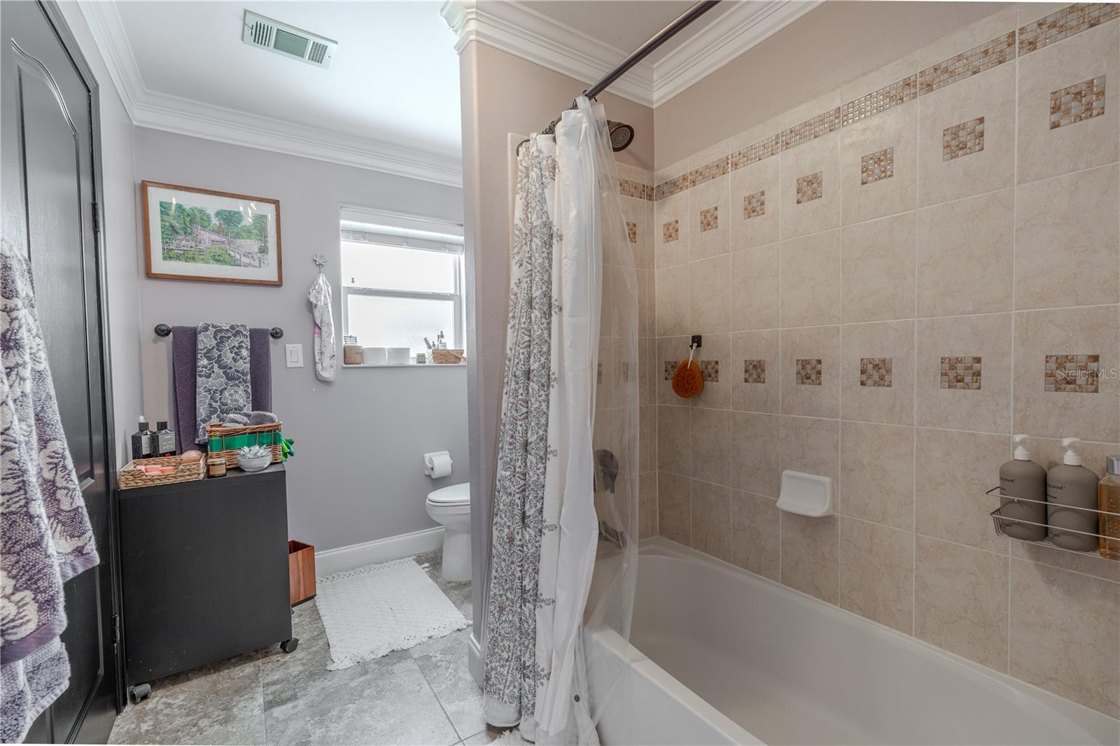 This thoughtfully designed upstairs Jack and Jill bathroom offers convenience and privacy with dual access from adjoining bedrooms.The space features a granite-topped vanity with rich wood cabinetry, dual mirrors, and elegant lighting. A separate water closet and shower/tub combination provide practical functionality, making it ideal for sharing. Neutral tilework and crown molding add a polished touch, while the layout ensures everyone has room to get ready in comfort and style.
