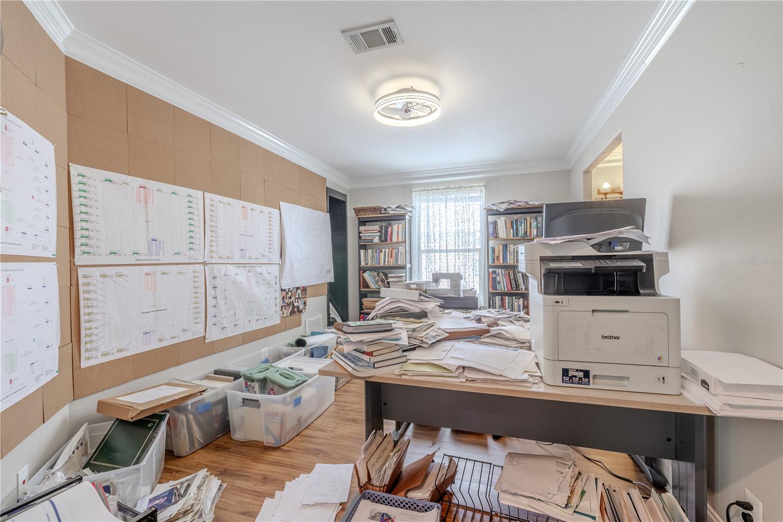 This upstairs 3rd bedroom is currently utilized as a dedicated home office , with a large window that fills the room with natural light. Crown molding, warm wood-look vinyl flooring, a modern ceiling fan and generous dimensions make it a versatile room ready to serve as a 3rd bedroom.